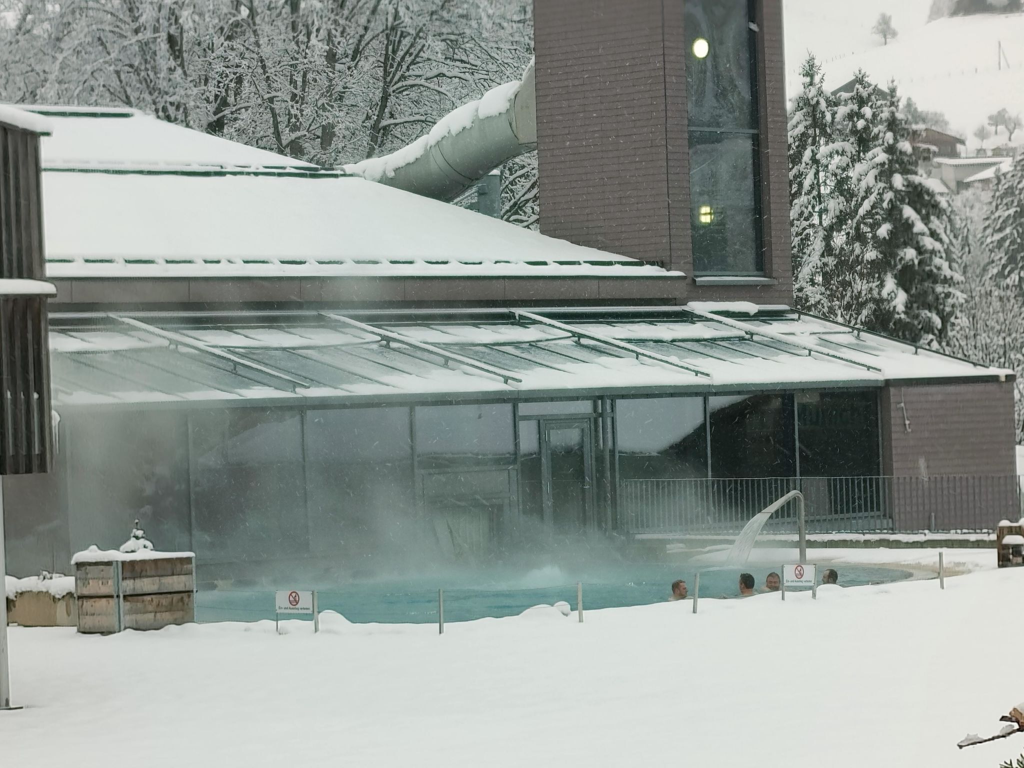 A building with a glass-enclosed swimming pool surrounded by snow.