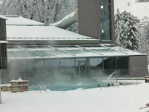 A building with a glass-enclosed swimming pool surrounded by snow. - Lenk Unique Appartement/Fewo, Dusche und Bad, WC, 2 Schlafräume 4-Bettwohnung by Interhome (Lenk)