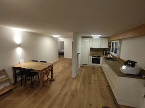 A compact kitchen with white cabinets, a wooden dining table, and a built-in oven. - Lenk Unique Appartement/Fewo, Dusche und Bad, WC, 2 Schlafräume 4-Bettwohnung by Interhome (Lenk)