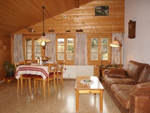 Ein gemütliches Blockhaus-Interieur mit Essbereich, einer Couch und einem Fenster mit Vorhängen.