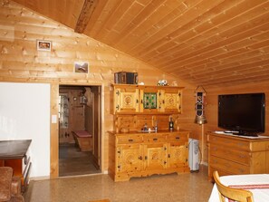 A wooden interior with a television, a cabinet with drawers, and a door leading to another room. - Ferienwohnung Haltenboden Appartement/Fewo, Bad, WC, 2 Schlafräume 3-Bettwohnung by Interhome (Boltigen)