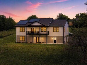Et toetagers hus med balkon, solpaneler og en godt oplyst indgang.