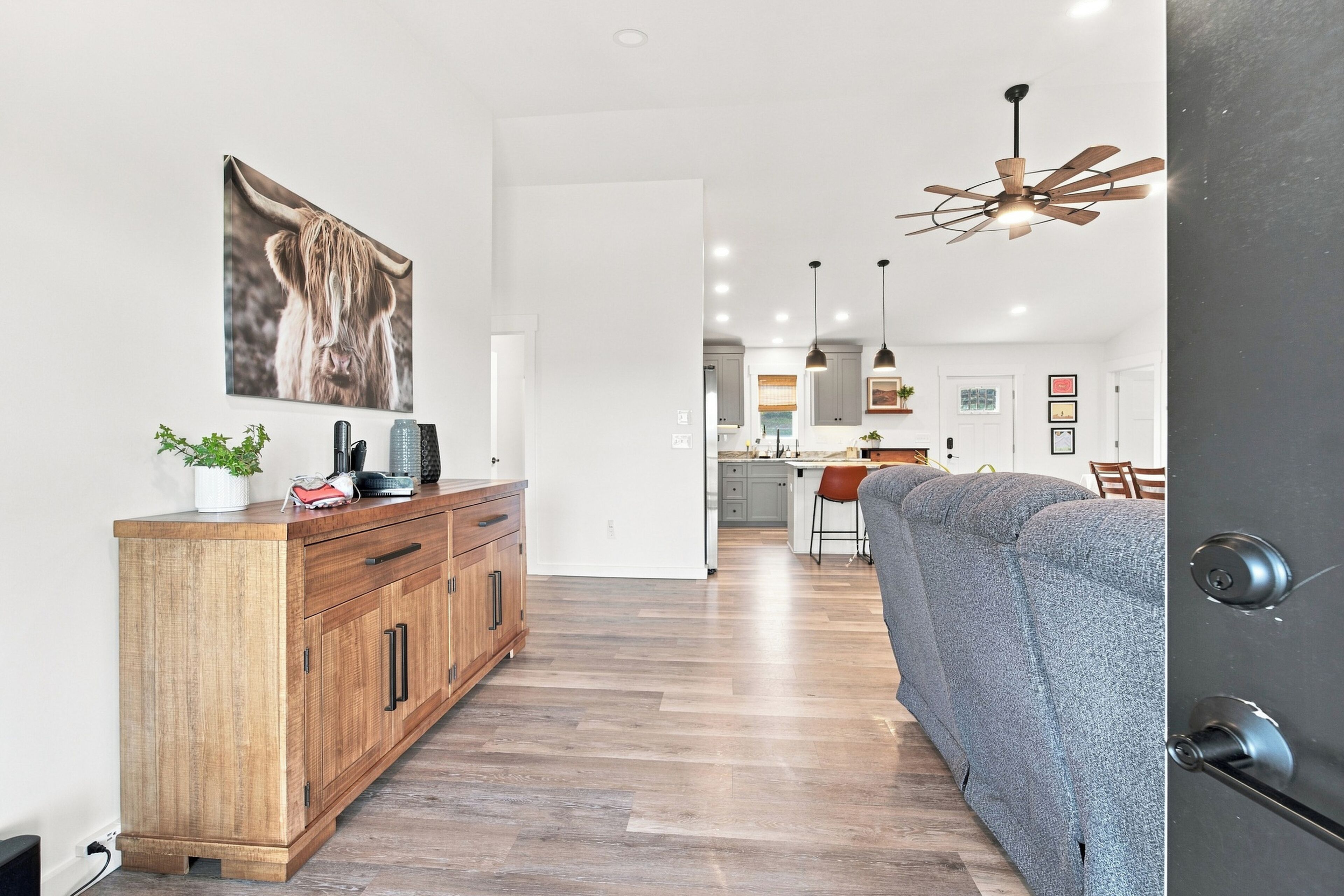 A modern kitchen with a central island, pendant lighting, and a view into the dining area.