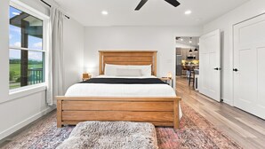 Un dormitorio con cama de madera, ventilador de techo y vistas a una cocina y comedor.