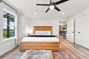 Ein Schlafzimmer mit einem hölzernen Bett, einem Deckenventilator und Blick auf eine Küche und einen Essbereich.