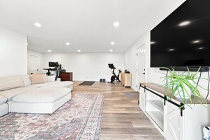 Ein modernes Wohnzimmer mit einer Couch, einem Teppich, einem Fernseher und Trainingsgeräten.