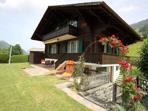 Eine Chalet mit Balkon, Rutsche und einem Blumengarten.