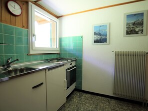 Eine Küche mit Fenster, Herd, Spüle und Heizkörper.