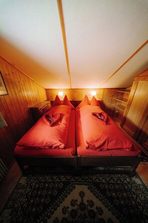 Ein Zimmer mit zwei Betten, Holzwänden und einem gemusterten Teppich.