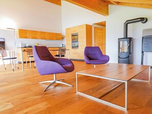 A modern living room with two purple chairs, a wooden coffee table, and a kitchen area with wooden cabinets and a stove. - Kronenplatz 11 OG Appartement/Fewo, Bad, WC, 2 Schlafräume 4 Bettwohnung by Interhome (Lenk)
