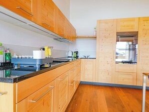 A modern kitchen with wooden cabinets, a stainless steel range hood, and a built-in oven. - Kronenplatz 11 OG Appartement/Fewo, Bad, WC, 2 Schlafräume 4 Bettwohnung by Interhome (Lenk)
