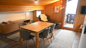 Ett mysigt rum med ett träbord och stolar, ett schackbräde, en bastu och ett stort fönster.
