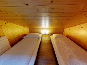 A cabin with two single beds, wooden walls, and a central light fixture. - Chalet Waldchutz - Wohnung Anax Appartement/Fewo, Dusche, WC, 2 Schlafräume by Interhome (Lenk)