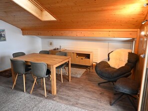 A cozy room with a wooden ceiling, a dining table with chairs, a fireplace, and a comfortable armchair. - Chalet Waldchutz - Wohnung Anax Appartement/Fewo, Dusche, WC, 2 Schlafräume by Interhome (Lenk)