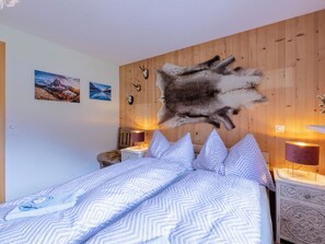 A bedroom with a bed, a wooden wall, and two wall-mounted lamps. - Chalet Lerchweid Lenk Appartement/Fewo, Bad, WC, 2 Schlafräume 4-Bettwohnung by Interhome (Lenk)