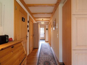 Ein Flur mit Holztüren, einem gemusterten Teppich und einer Decke mit sichtbaren Holzbalken.