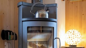 Ein Kaminofen mit Glastür, einem Metallschornstein und einer dekorativen Lampe.