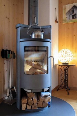 Ein Kaminofen mit Glastür, einem Metallschornstein und einer dekorativen Lampe.