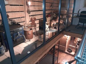 Ein mehrstöckiges Holzinterieur mit Küchenzeile, einem Esstisch und einem Glasgeländer, das auf die untere Ebene blickt.