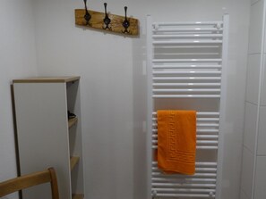 A bathroom with a white towel rack, a wooden shelf, and a white radiator. - Kari's Schüür Appartement/Fewo, Dusche, WC, 2 Schlafräume 5-Bettwohnung by Interhome (Lenk)