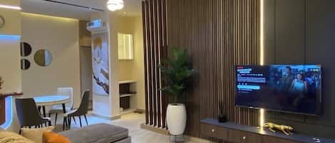 Una sala de estar moderna con sofá, mesa de centro, televisor y elementos decorativos.