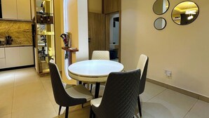 Un comedor moderno con una mesa redonda y cuatro sillas, una cocina con nevera empotrada y una pared con tres espejos redondos.