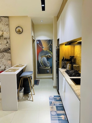 A narrow kitchen with a dining area, a sink, and a stove. - H and H Apartment (Port Harcourt)
