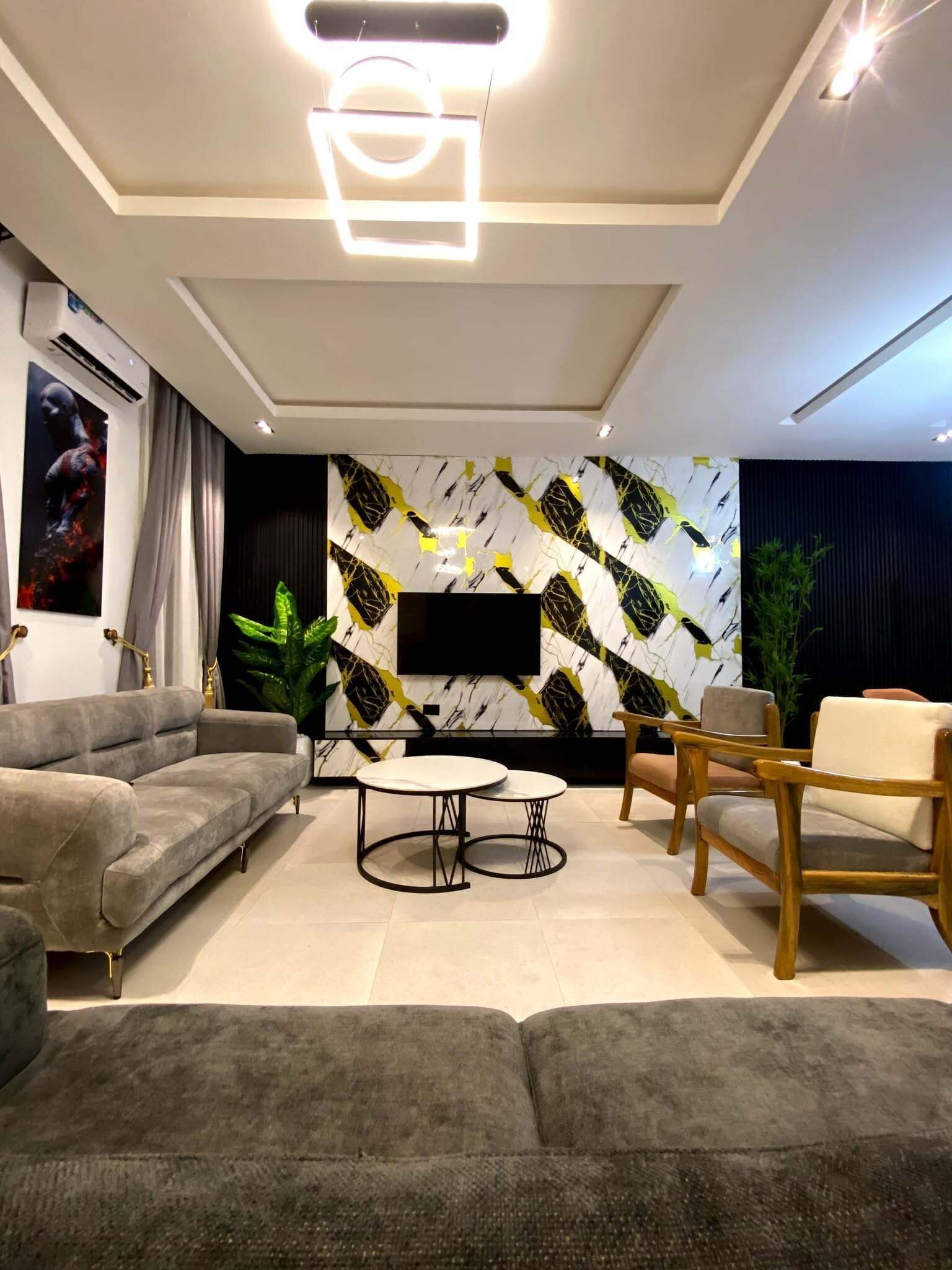 A modern living room with a grey sofa, a coffee table, and wooden chairs.