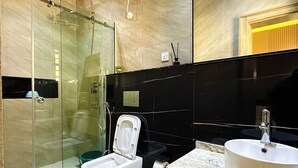 Un baño moderno con cabina de ducha de vidrio, inodoro, lavamanos y espejo.