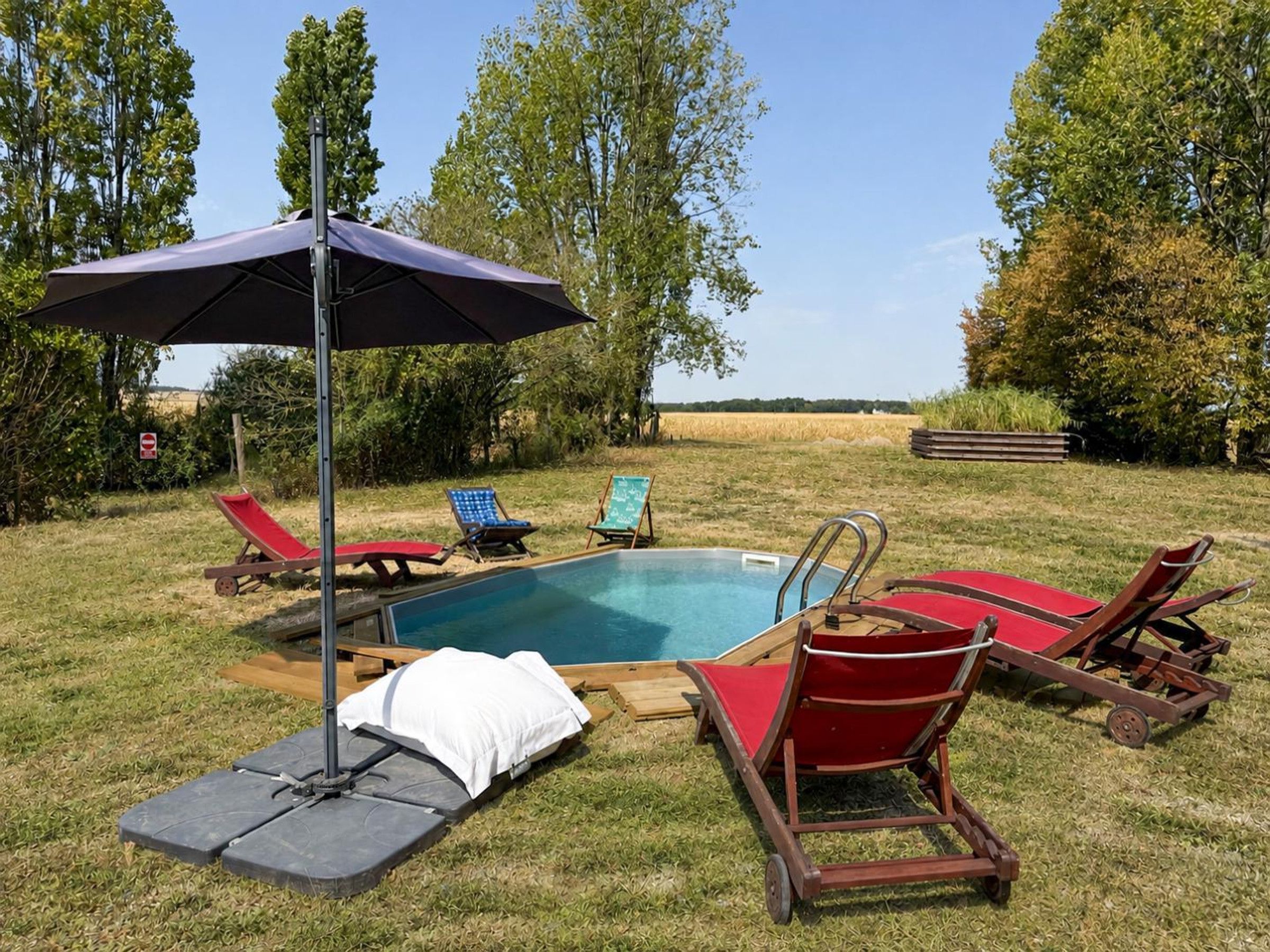 En baghave med swimmingpool, liggestole og parasol.
