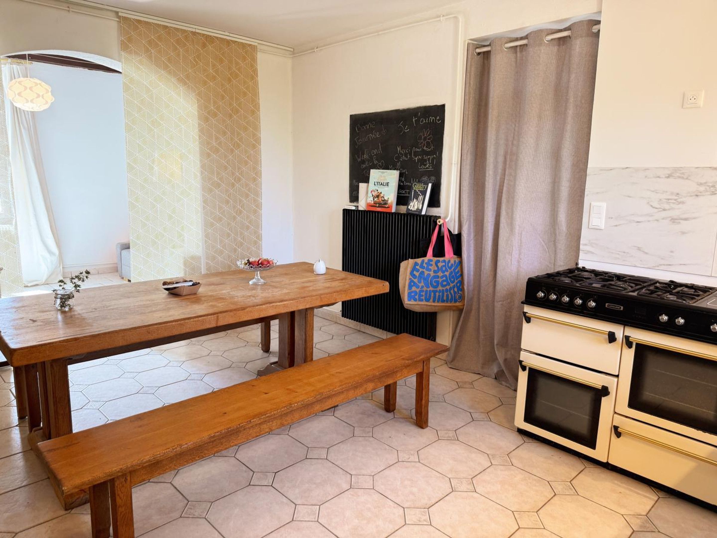 Una cocina con una mesa de madera, un banco, una estufa y un radiador.