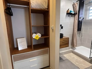 A hotel room with a wooden wardrobe, a shower area, and a small shelf with towels. - Villa panoramic view, air conditioning - 8 guests (Saint-Philippe)