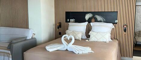 Une chambre d’hôtel avec un lit, un canapé et un mur recouvert de panneaux en bois.
