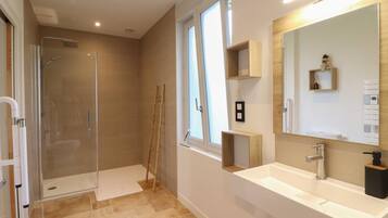 Une salle de bain moderne avec une douche à parois de verre, un lavabo blanc et un grand miroir.