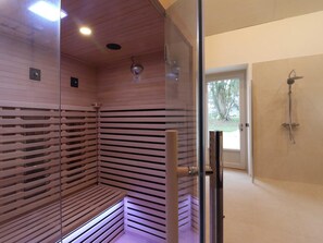 Una sauna con listones de madera, una puerta de cristal y una zona de ducha con puerta de vidrio.