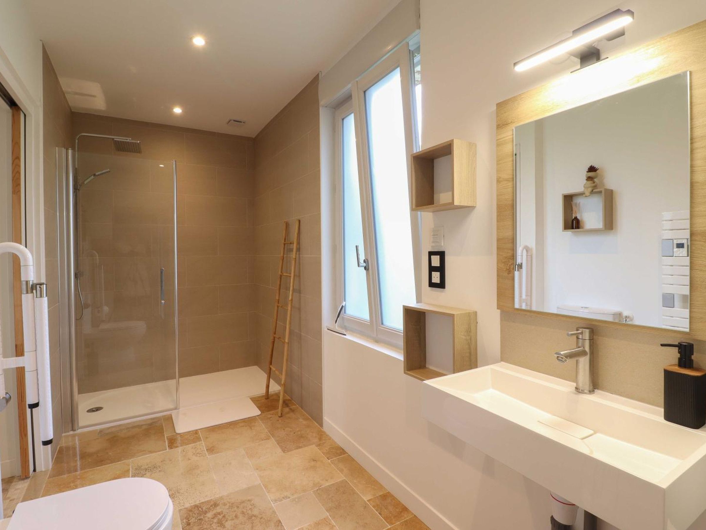 Un baño moderno con cabina de ducha de vidrio, un lavabo blanco y un espejo grande.