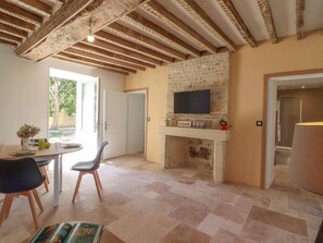 Una habitación con chimenea, un televisor montado encima y una zona de comedor con sillas y mesa.