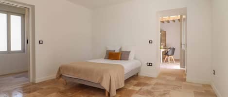 A bedroom with a bed, a door, and an air conditioning unit.