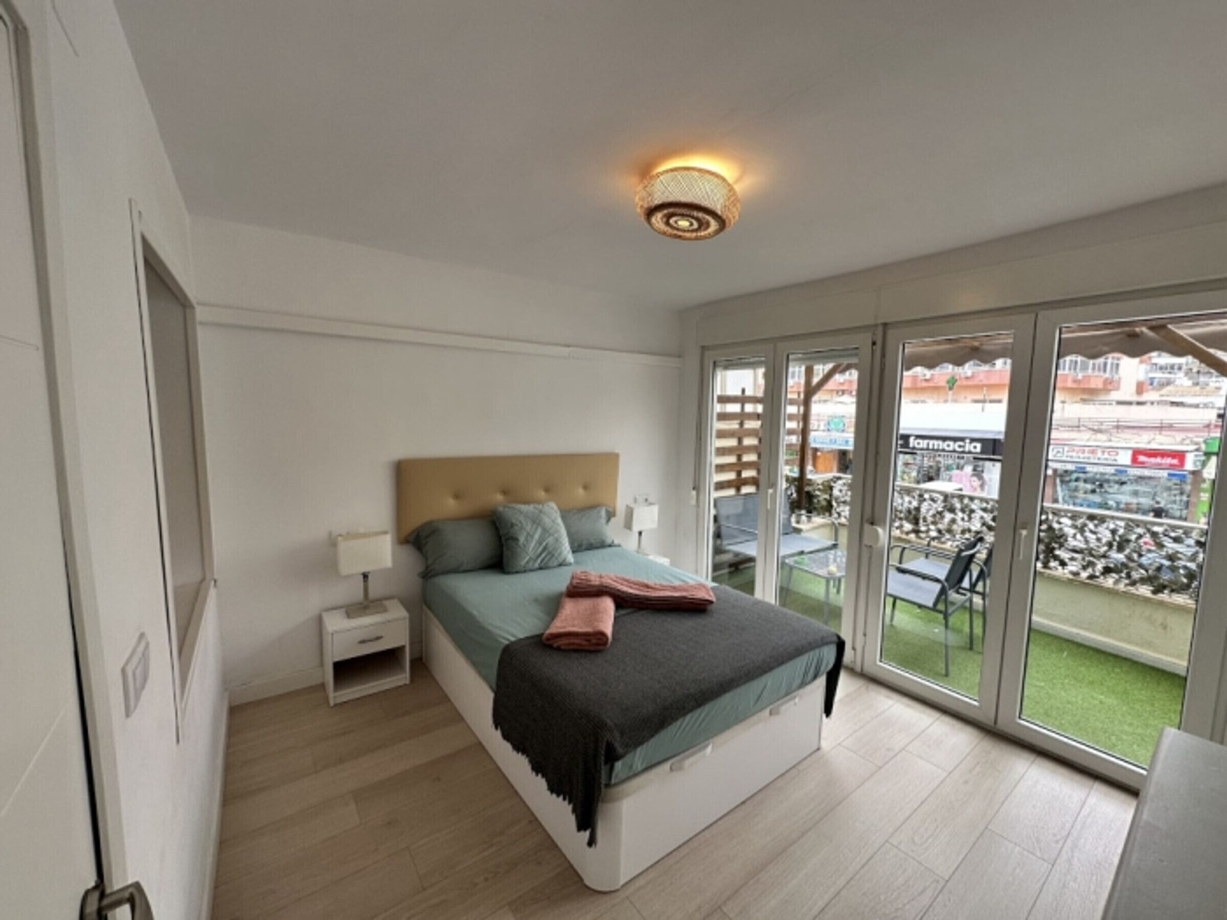 Une chambre à coucher comprenant un lit, une table de chevet et donnant sur un balcon aménagé avec des sièges d’extérieur.