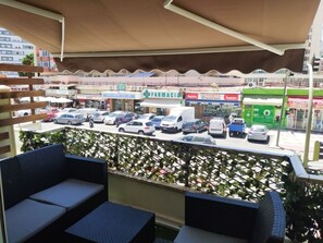 A balcony with outdoor seating, a view of a parking lot with various vehicles, and a pharmacy in the background. - Central Apartment with Terrace and Air Conditioning (Torremolinos)