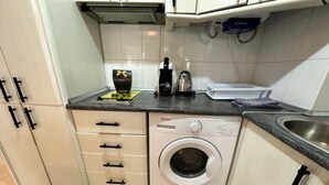 A compact kitchen with a built-in washing machine, a kettle, and a coffee maker on the countertop. - Central Apartment with Terrace and Air Conditioning (Torremolinos)