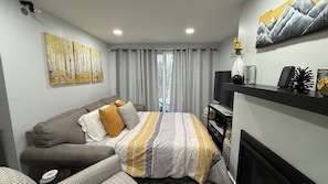 Ein Schlafzimmer mit Bett, Sofa, Fernseher und Kamin.