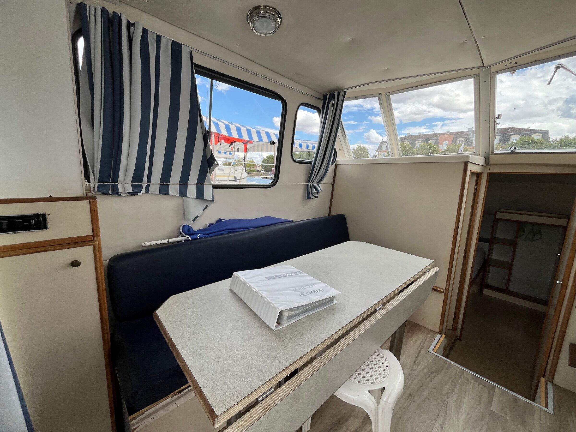 Et kompakt interiør med en seng, et lille bord og et vindue med gardiner.
