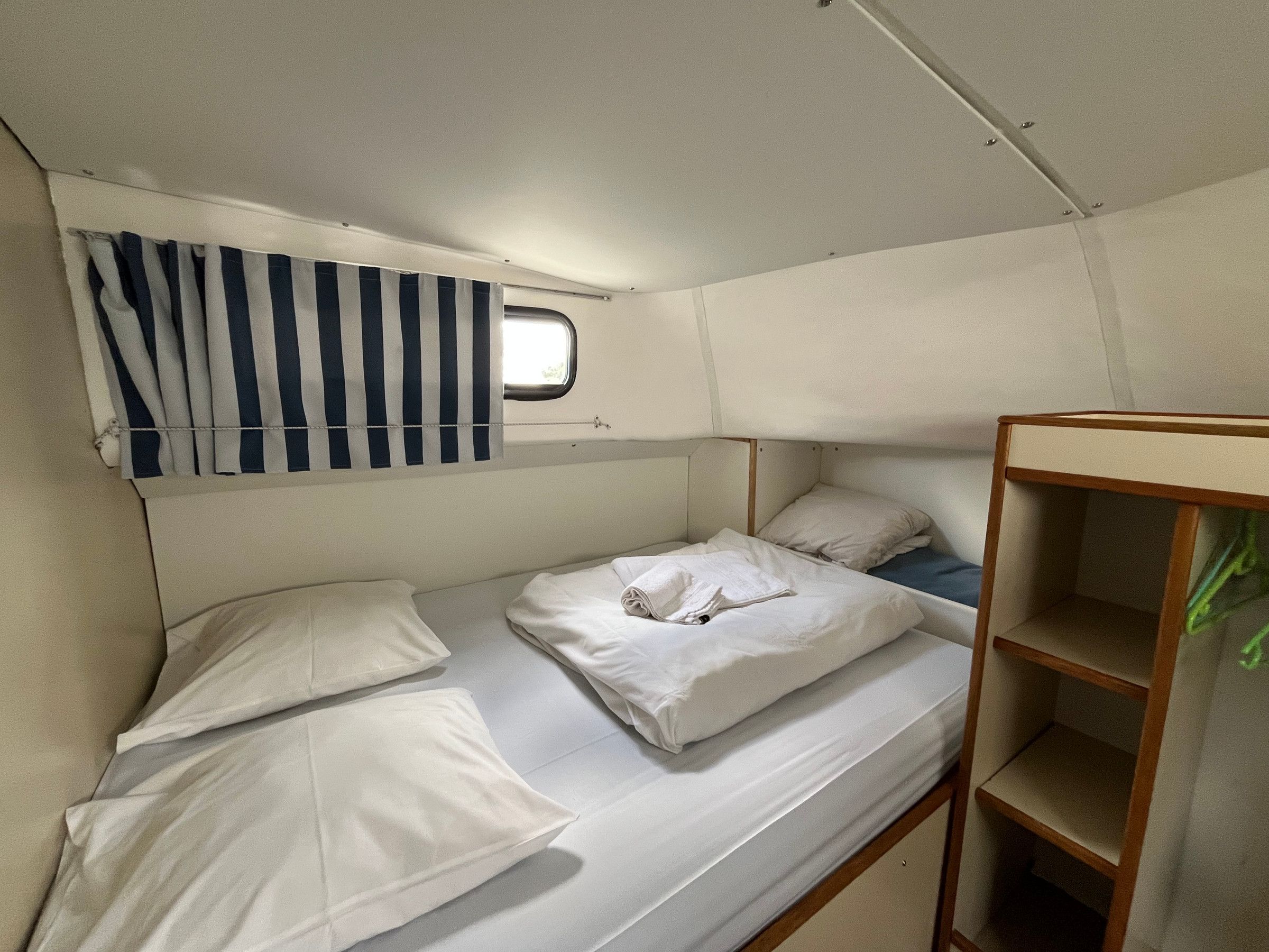 A bunk bed with white bedding and a window above it.