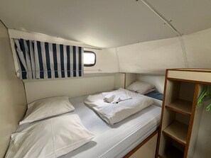 Ein Stockbett mit weißer Bettwäsche und einem Fenster darüber.