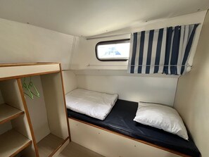 A compact room with a bunk bed, a small window with a view, and a curtain.