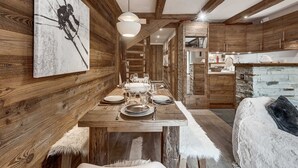 A rustic interior with wooden walls, a dining table set for four, and a cozy seating area. - Apartment with parking - 6 guests (Val d'Isère)