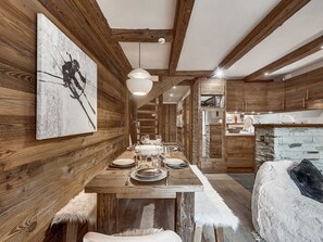 A rustic interior with wooden walls, a dining table set for four, and a cozy seating area. - Apartment with parking - 6 guests (Val d'Isère)