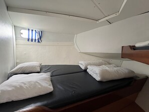 Una cabina compatta con un letto singolo, una piccola finestra con tende e uno scaffale integrato.