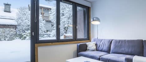 Un salon moderne avec une grande fenêtre, un canapé, une table basse et une lampe.
